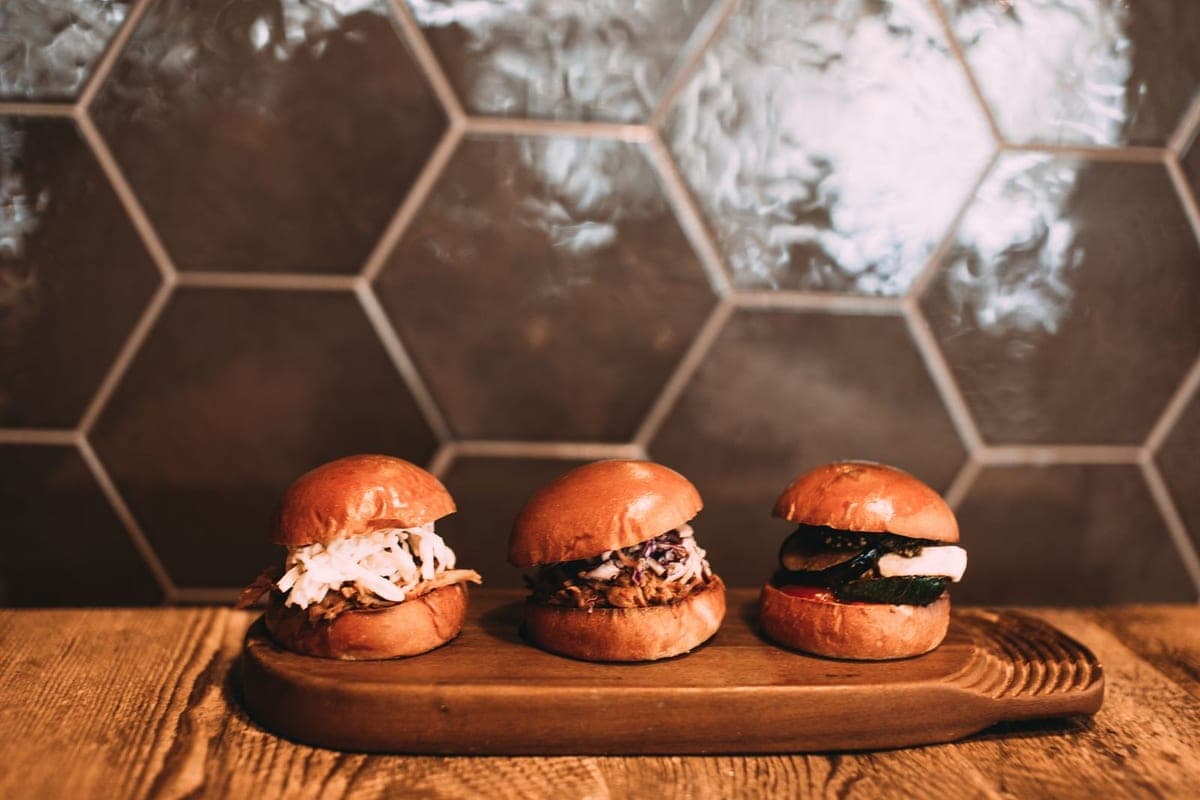 Three slider burgers on a wooden board